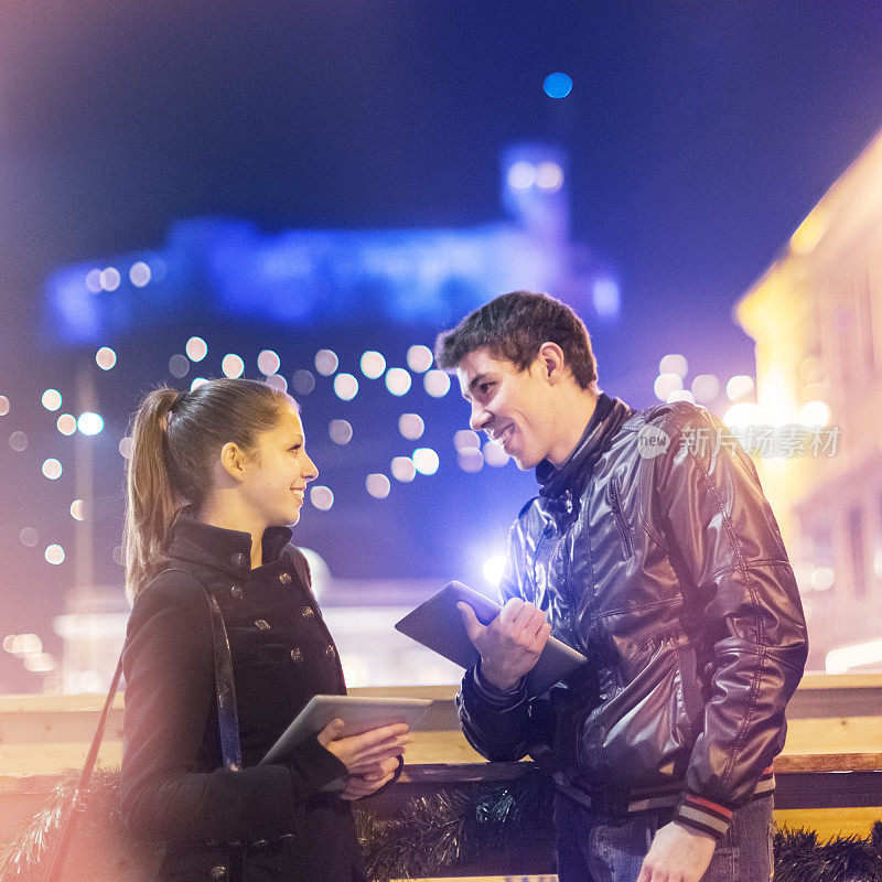 Young adults with digital tablets flirting on the street